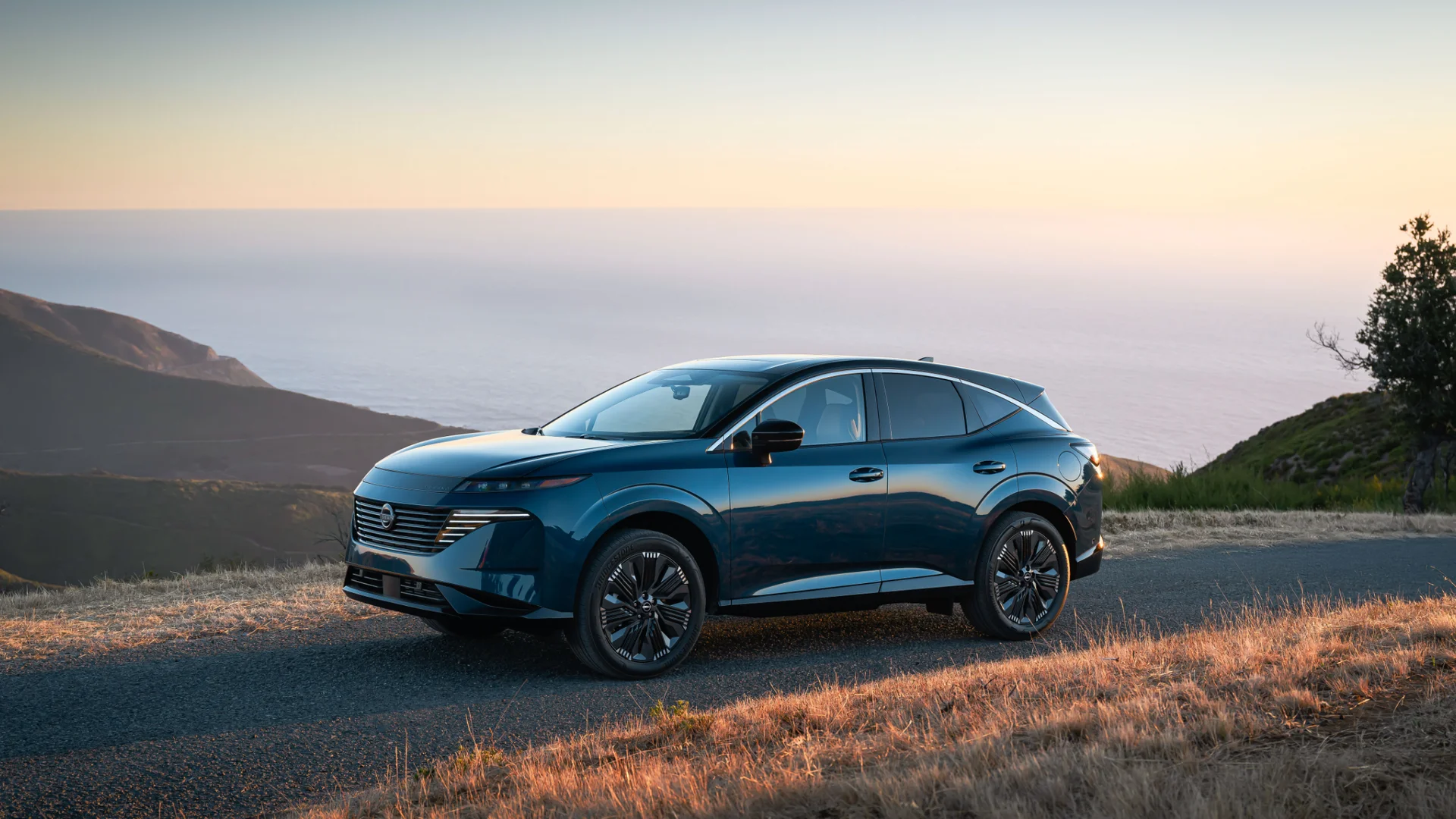 2026 Nissan Murano® in dark blue parked on a coastal route at sunset with ocean views in background.