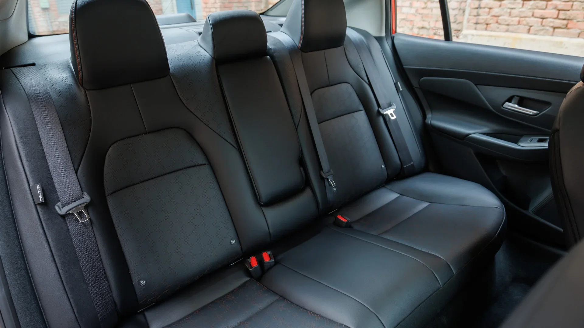 2025 Nissan Sentra® rear cabin with black seating red accents and three passenger headrests in view.