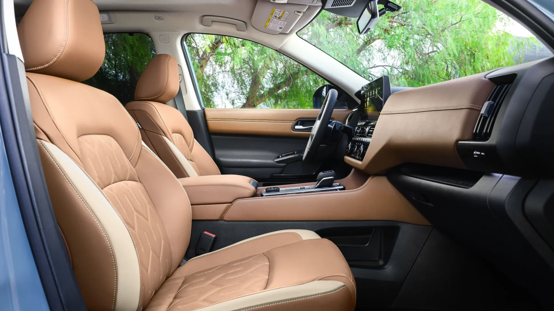 2026 Nissan Pathfinder® front cabin with brown quilted seats, touchscreen and upscale interior trim.