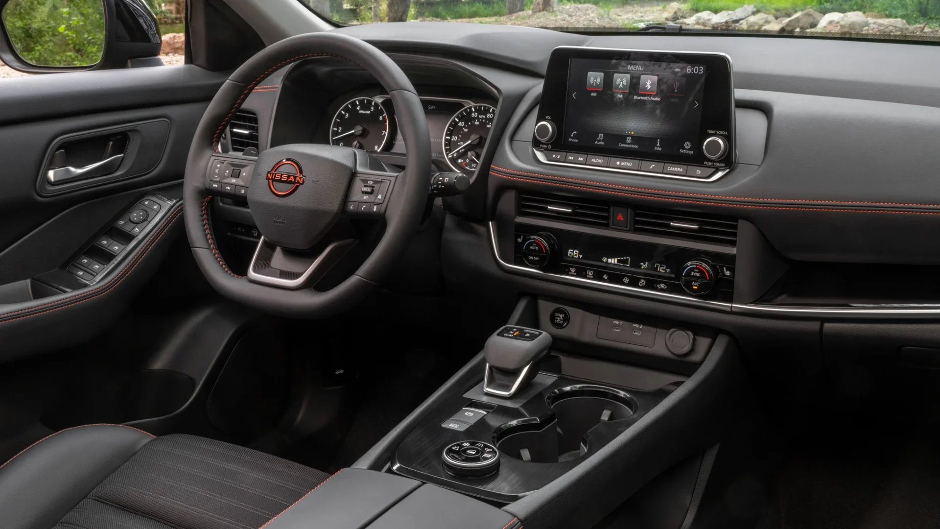 2026 Nissan Rogue® dashboard with steering wheel infotainment screen and orange-accented cabin trim.