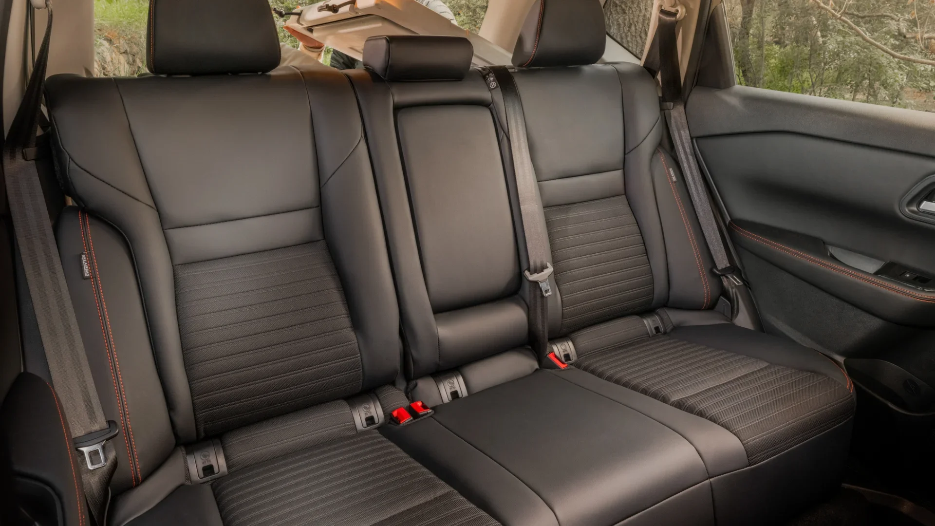 2026 Nissan Rogue® rear seats in black upholstery with orange contrast stitching and center armrest.